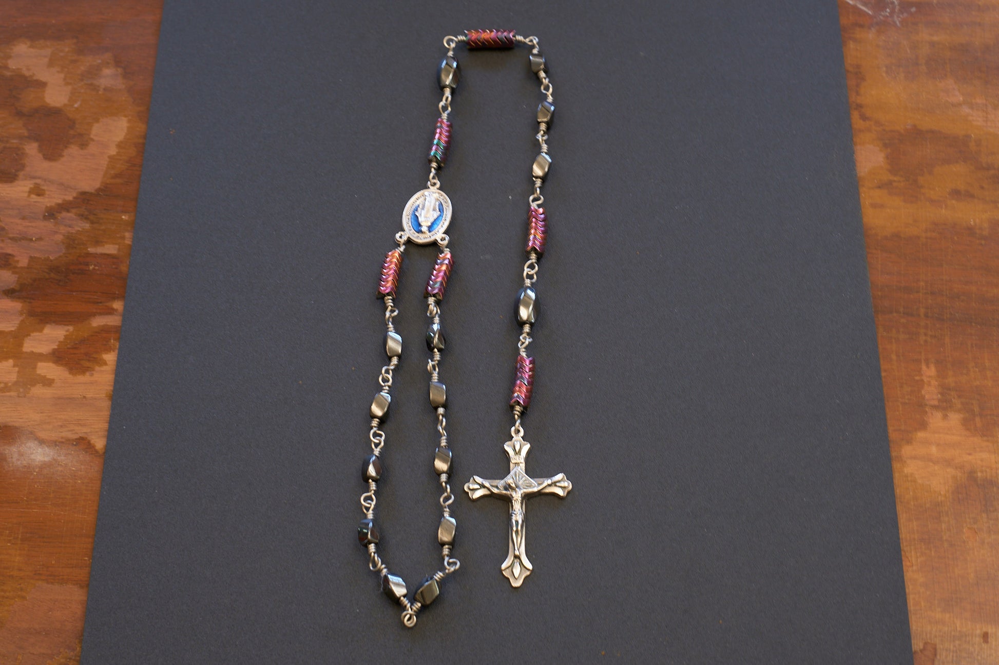 single decade rosary with oval faceted hematite beads and blue miraculous medal centerpiece