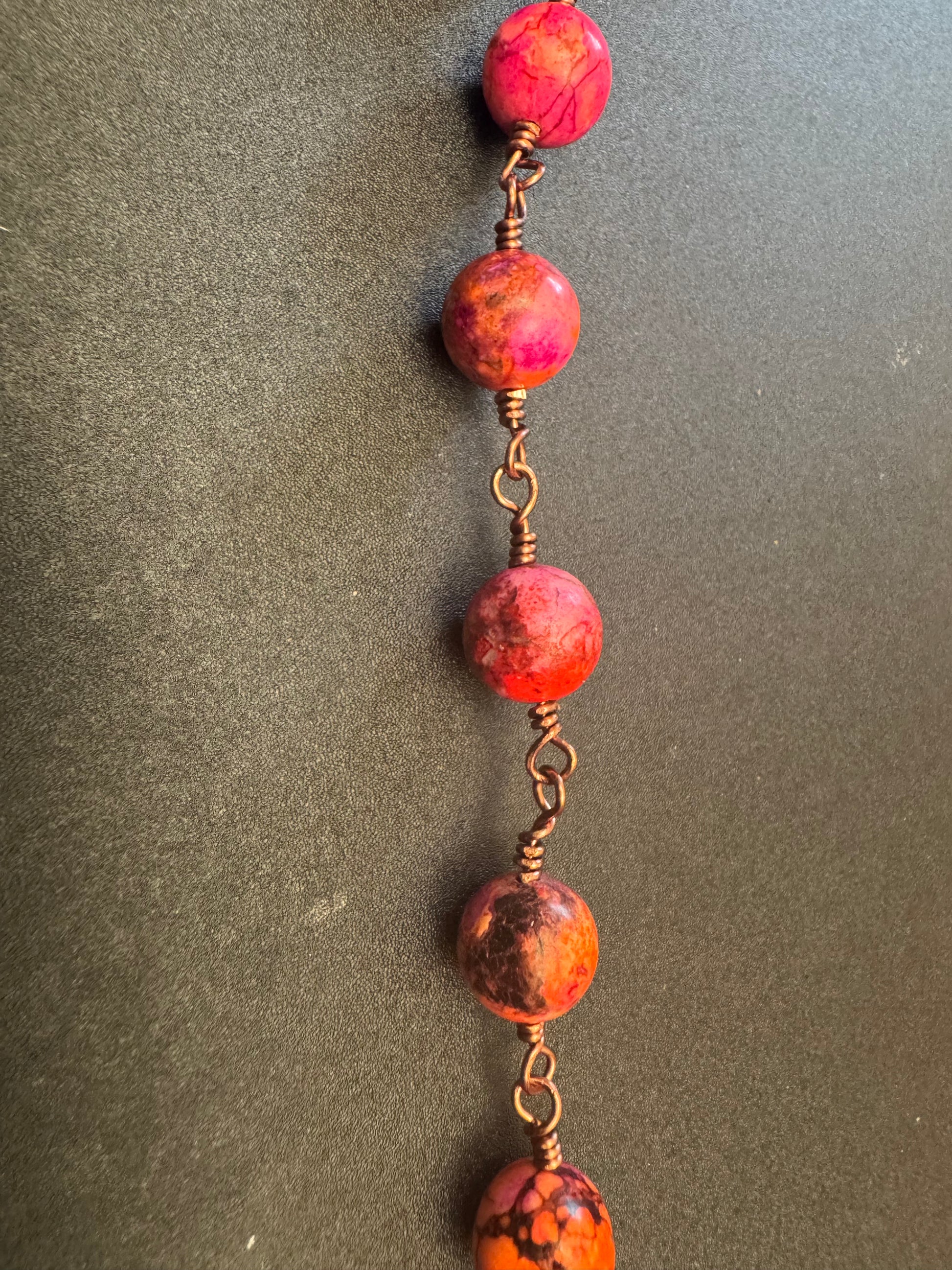Closeup of Holy Spirit Pocket Rosary with pinkish orange beads and wooden crucifix