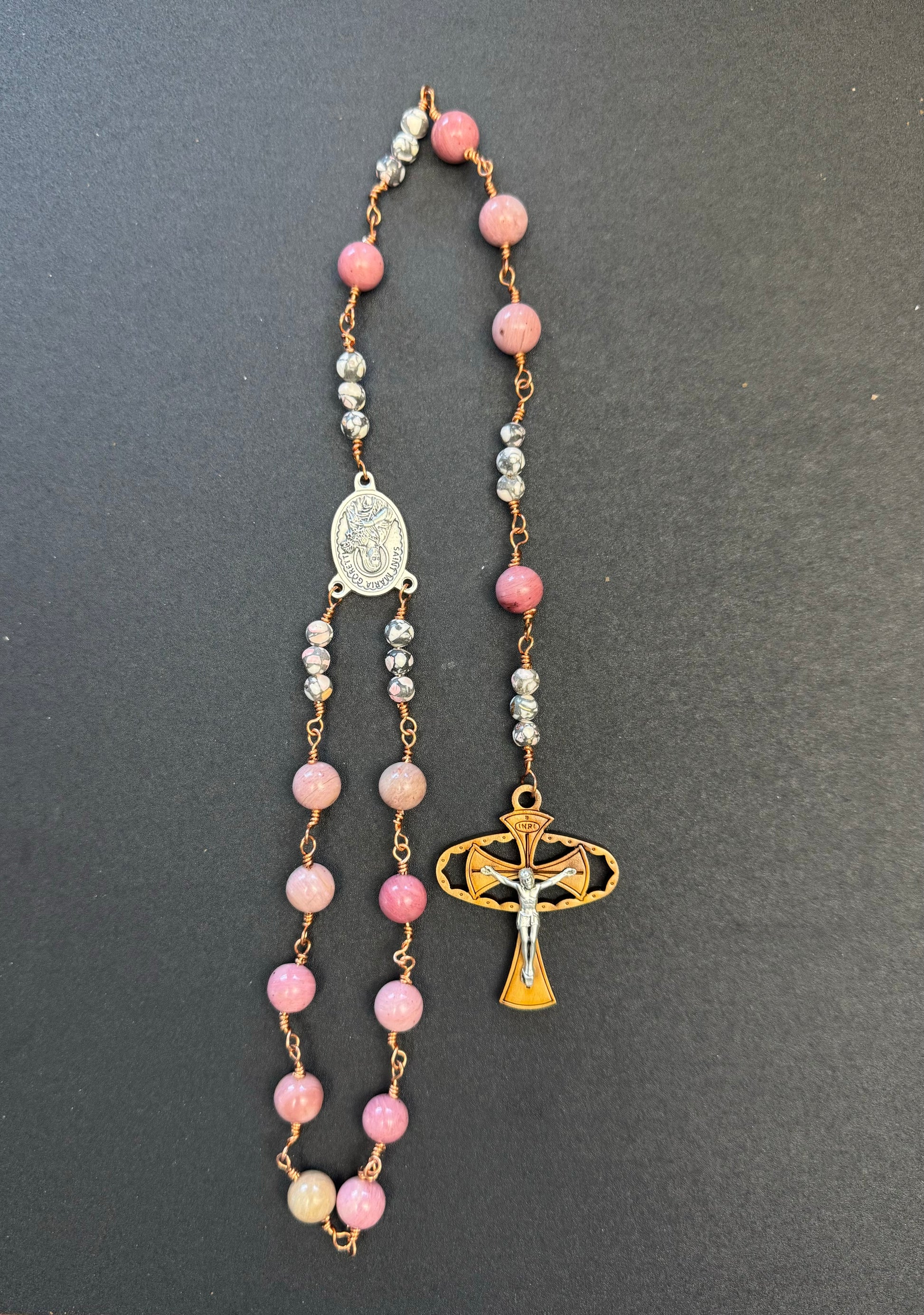 Top down view of St. Maria Goretti Single Decade Rosary with pink stone beads and wooden crucifix