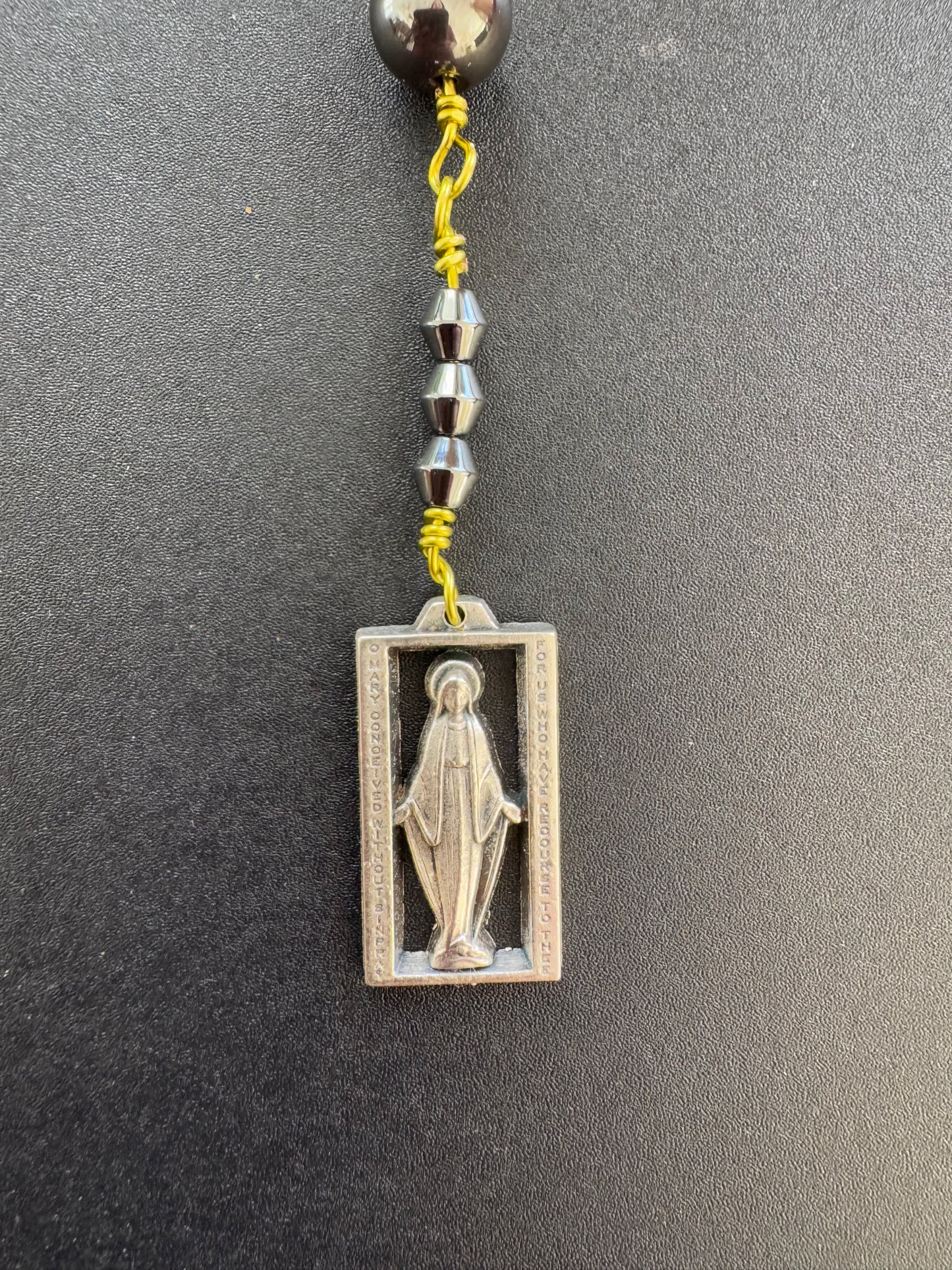 closeup of square Mary medal on chaplet of the immaculate conception