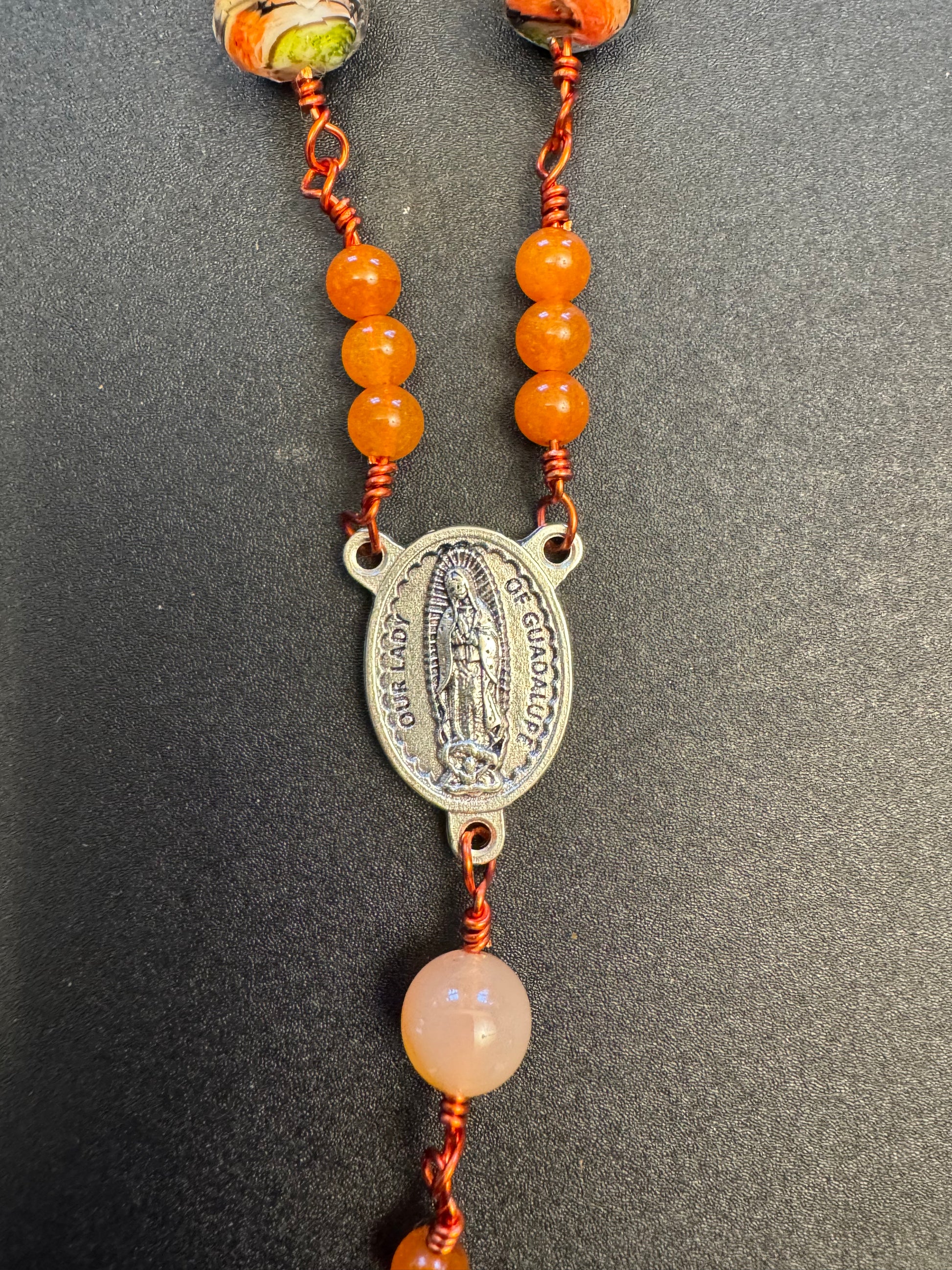 Our lady of Guadalupe centerpiece on single decade our lady of Guadalupe rosary with green and orange swirl glass beads and orange colored wire