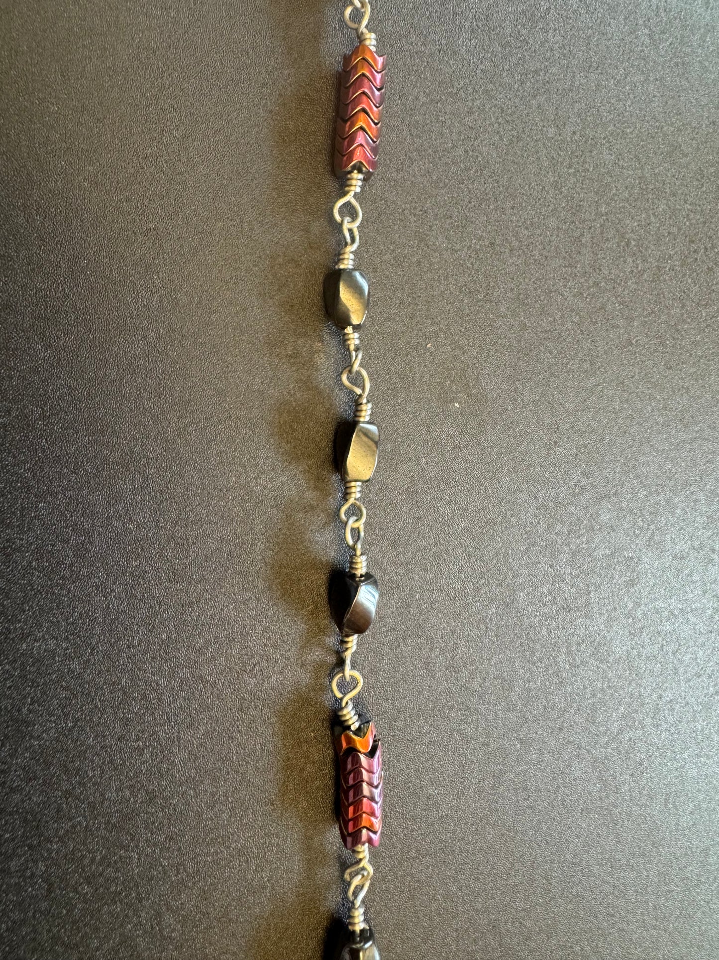 Closeup of single decade rosary with oval faceted hematite beads and blue miraculous medal centerpiece