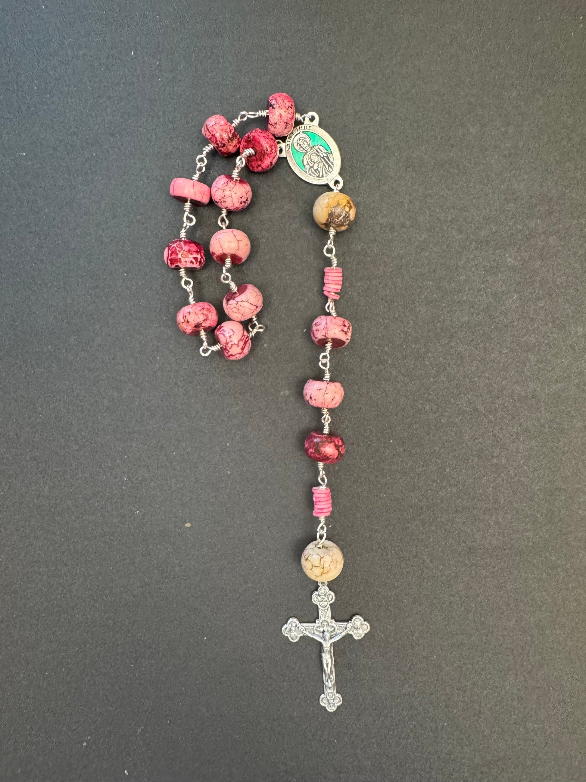 Top down view of St. Jude Single Decade Rosary With pink stone beads and green accented centerpiece
