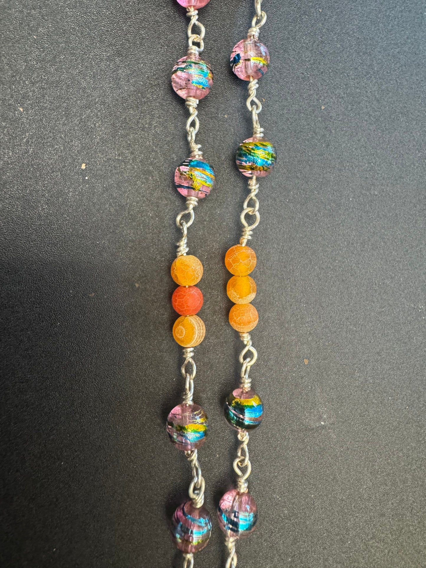 Closeup of full size rosary with multicolored glass and orange agate beads