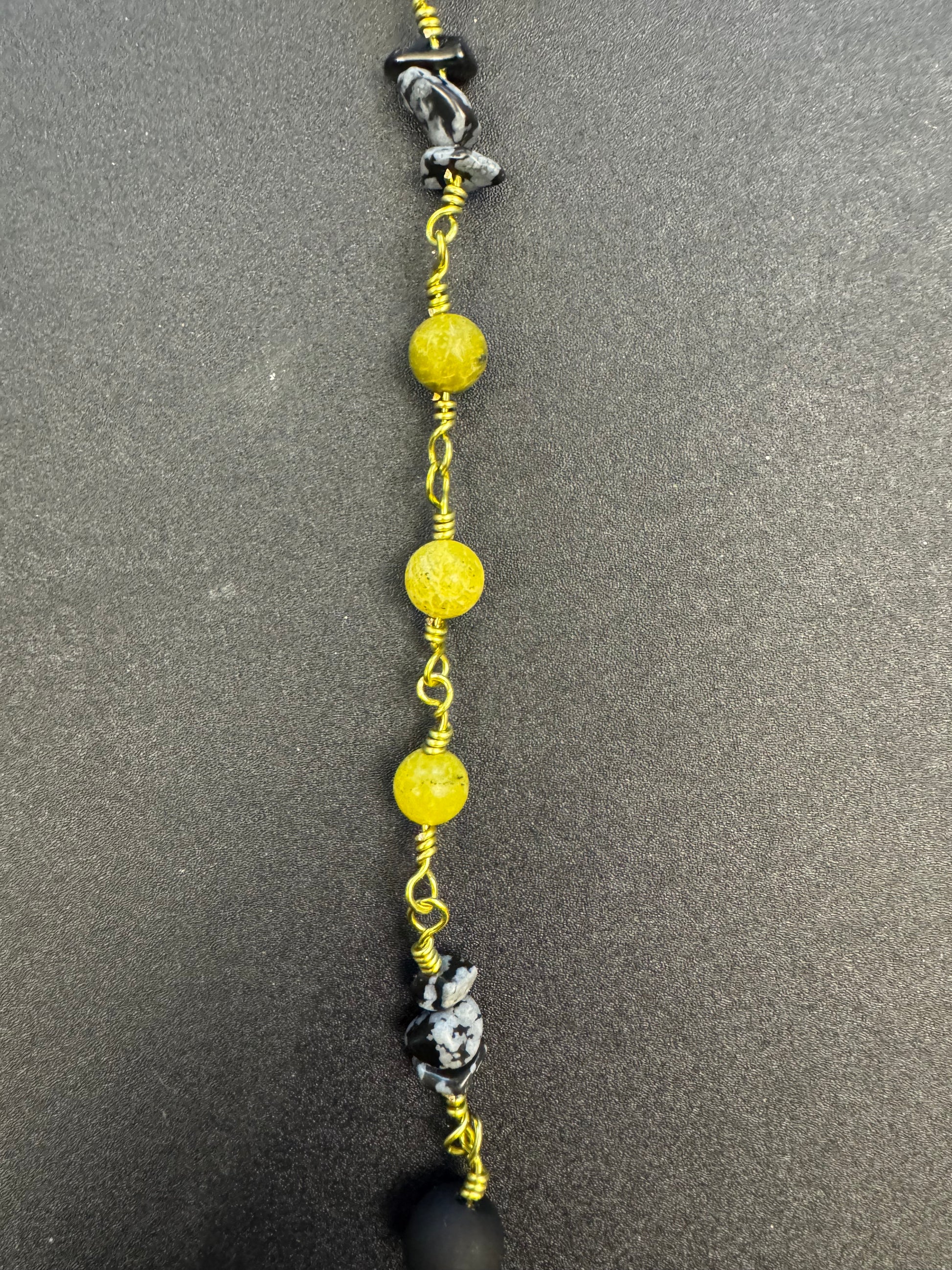 Closeup of single decade rosary with matte black agate and green serpentine beads with lime green colored wire