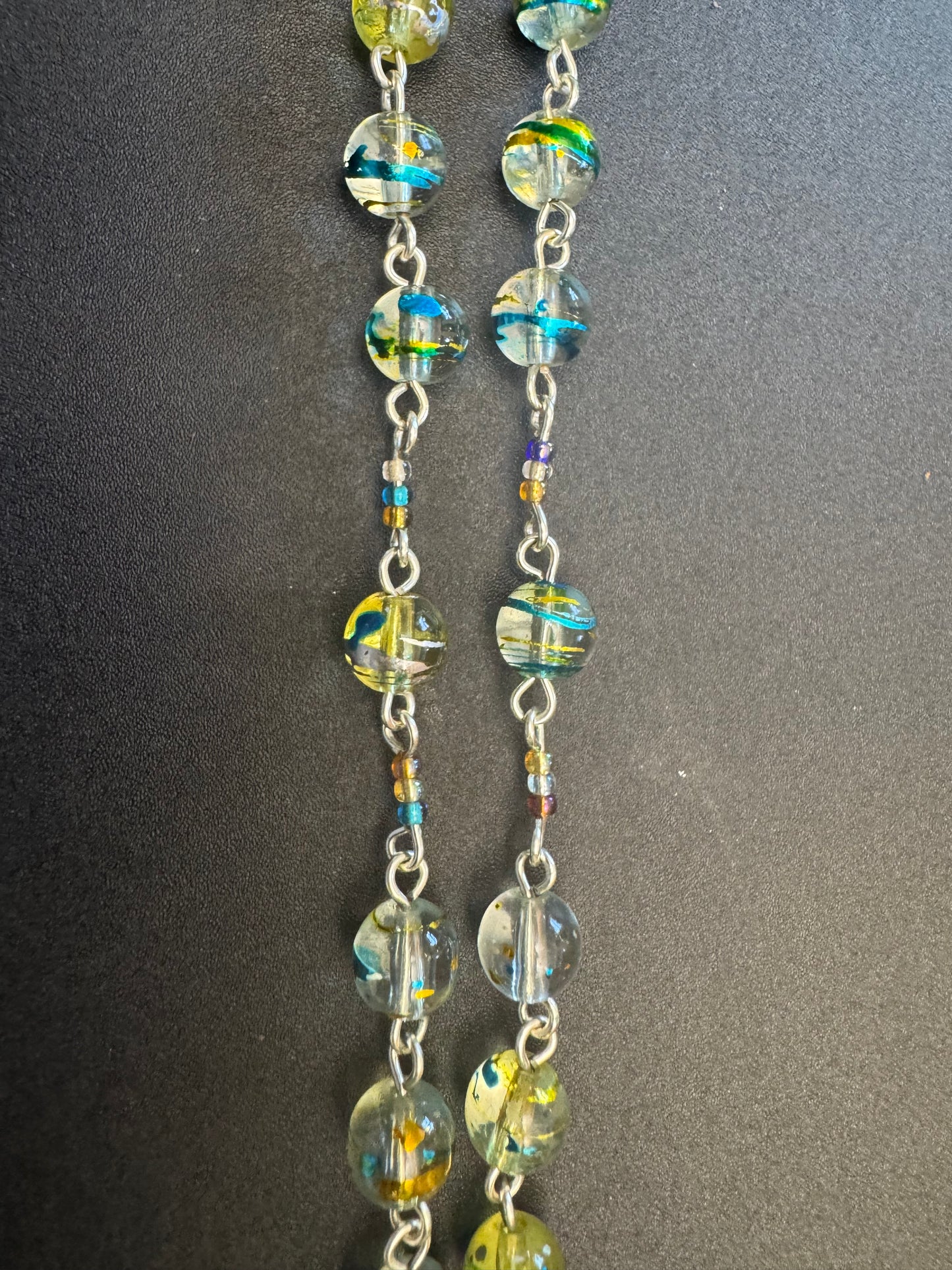 Closeup of Blue and green swirl glass bead rosary with crown of thorns centerpiece