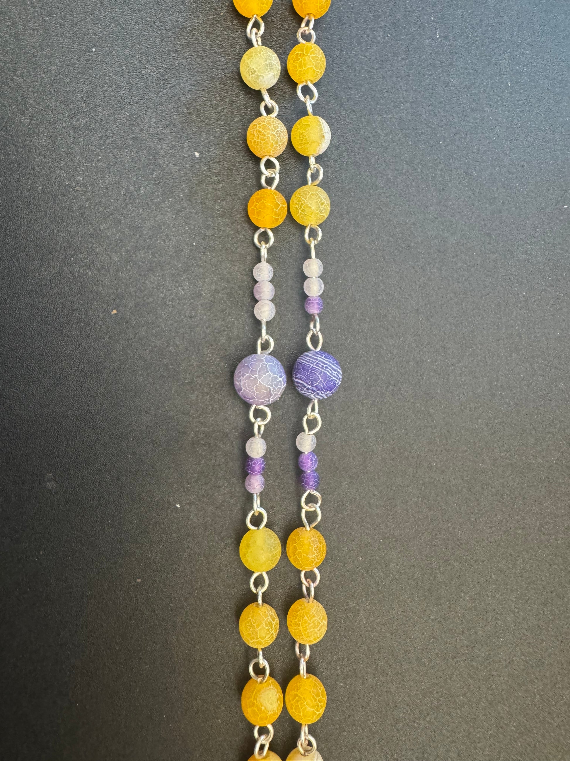 closeup of pater beads on orange and purple frosted bead rosary