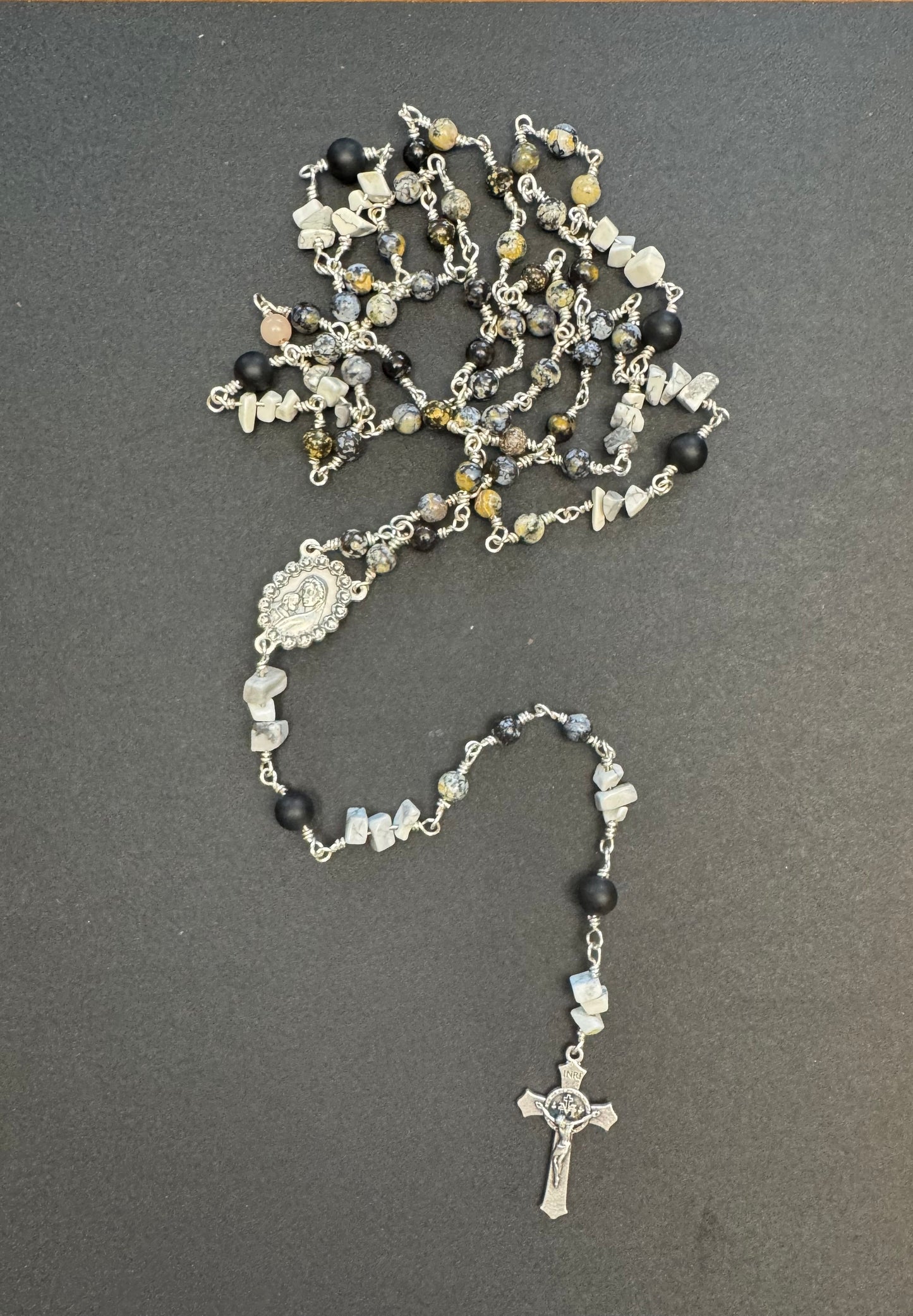 Top down view of full size rosary with gray and black stone beads
