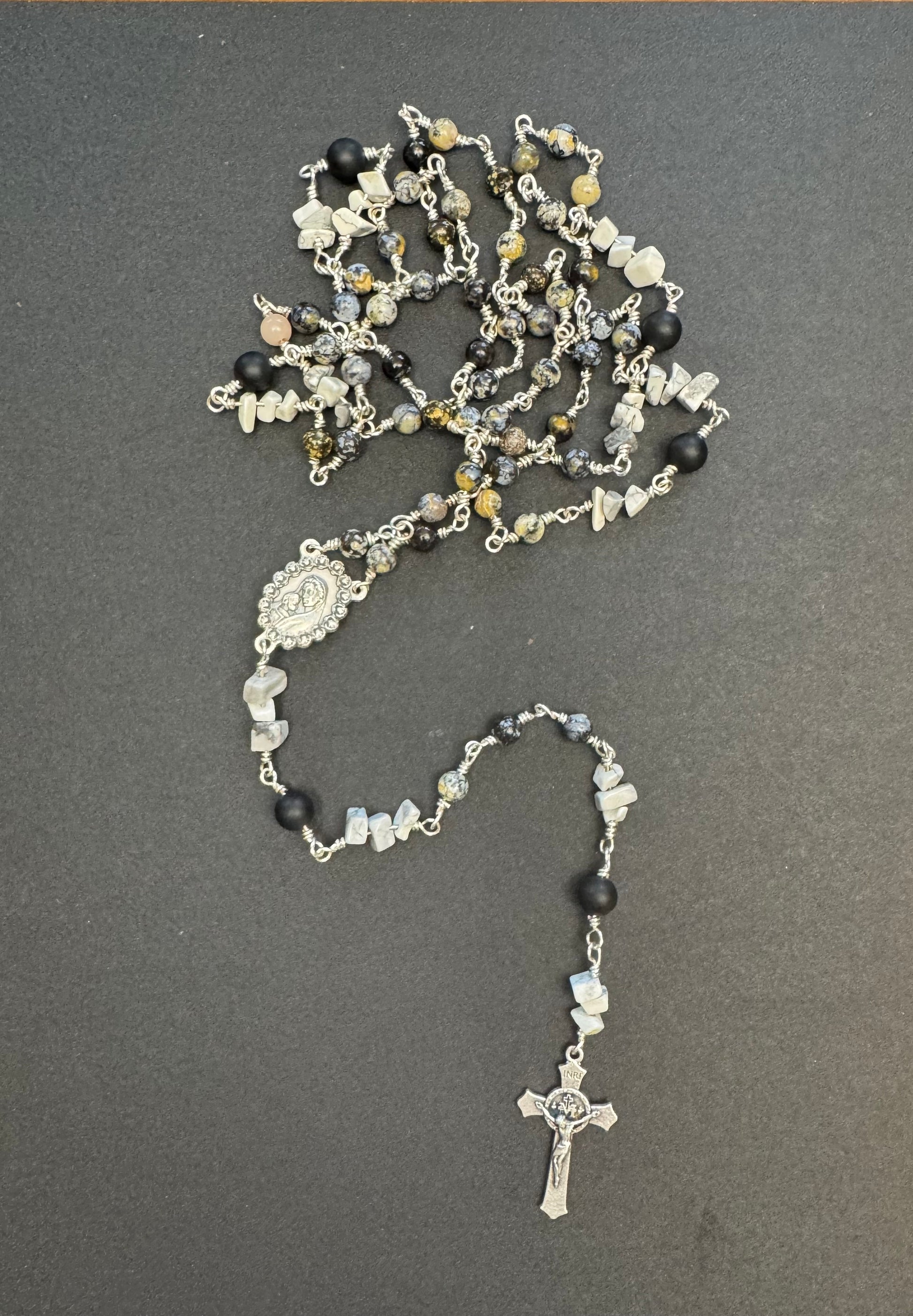 Top down view of full size rosary with gray and black stone beads