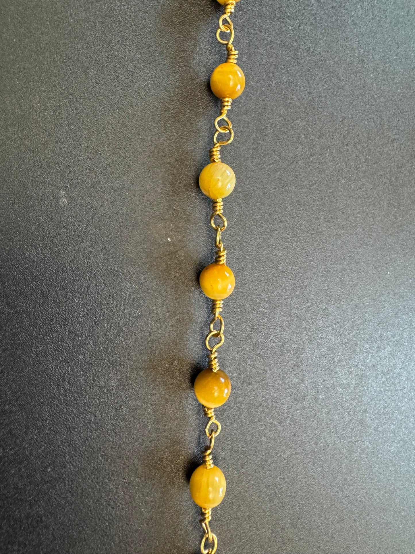 Closeup view of Tiger eye pocket rosary with gold plated wire and crucifix