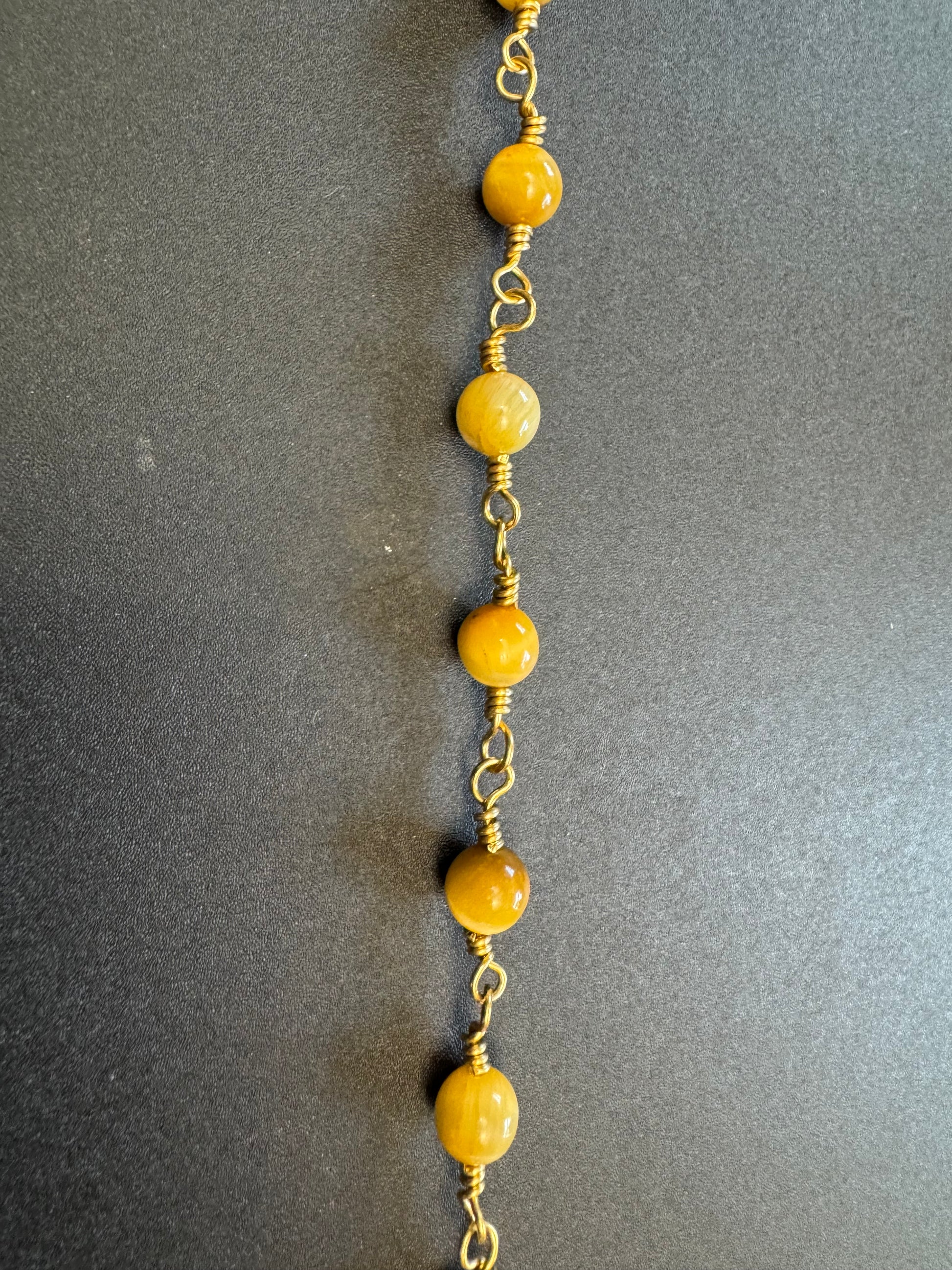 Closeup view of Tiger eye pocket rosary with gold plated wire and crucifix