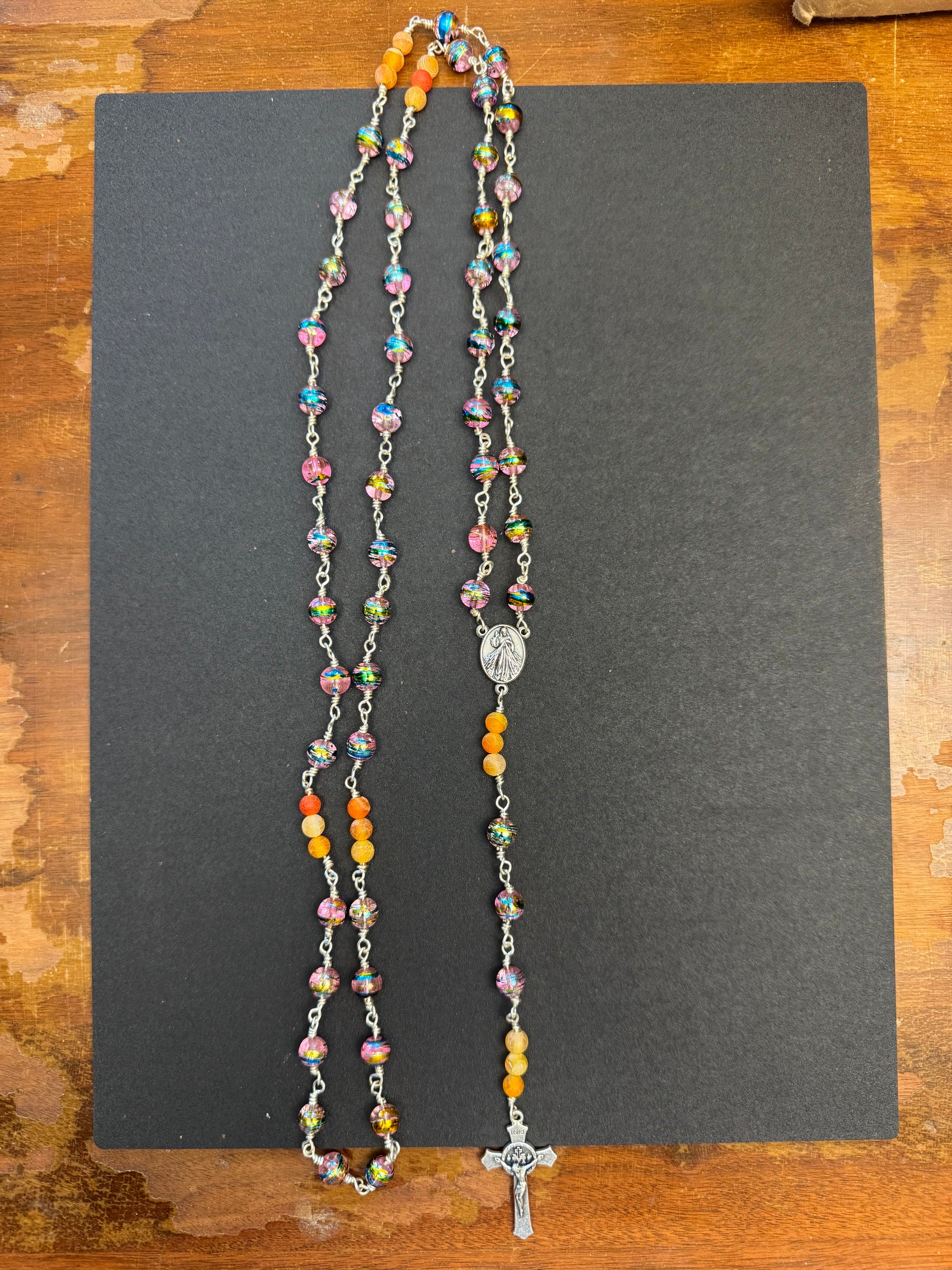 Zoomed out perspective of full size rosary with multicolored glass and orange agate beads
