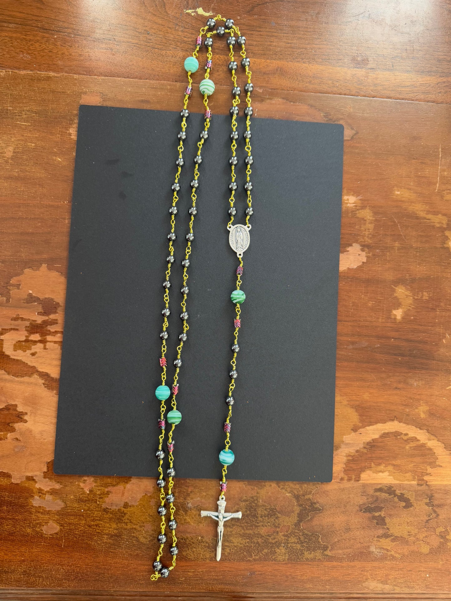 zoom out of hematite rosary with green wire
