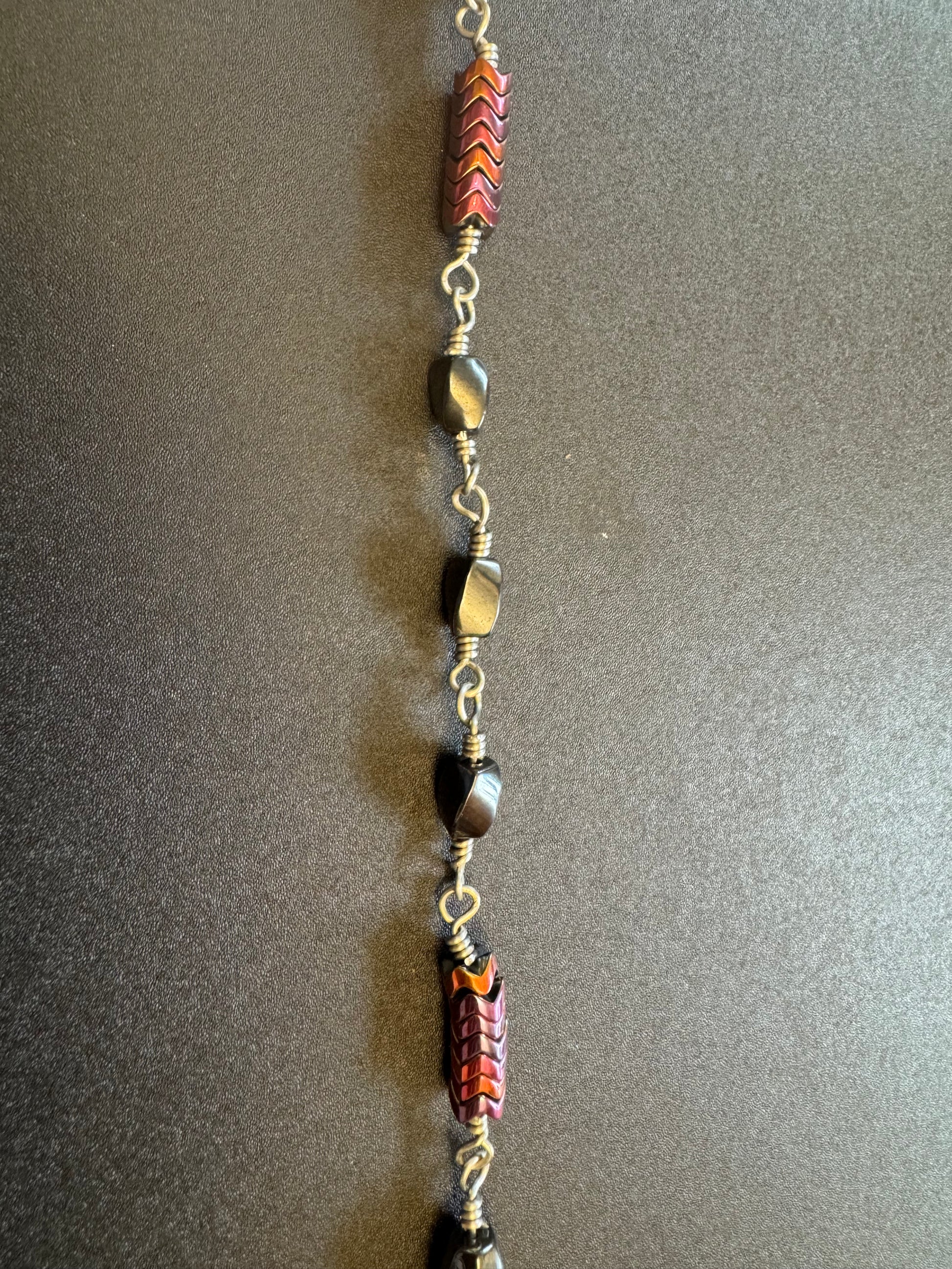 Closeup of single decade rosary with oval faceted hematite beads and blue miraculous medal centerpiece 